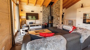 Un salon chaleureux avec une cheminée, des poutres en bois et un mur en pierre.