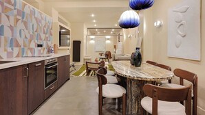 Una cocina moderna con armarios de madera oscura, horno empotrado y una mesa de comedor de mármol con seis sillas.