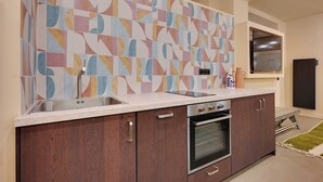Una cocina moderna con un salpicadero de azulejos geométricos, electrodomésticos de acero inoxidable y armarios de madera.