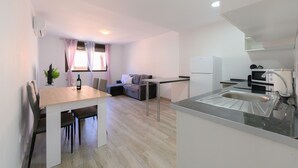 Una cocina moderna con comedor, refrigerador, pileta y ventana con cortinas.