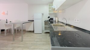 Una cocina moderna con encimera negra, armarios blancos y refrigerador blanco.