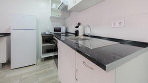 Een moderne keuken met witte kastjes, een zwart aanrecht, een magnetron en een inbouwoven.