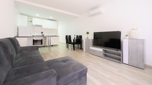 Een moderne woonkamer met een grijze bank, een flatscreen televisie en een minimalistisch design.