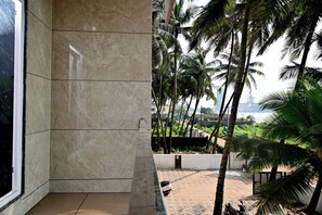 A room with a marble wall and a view of palm trees and a distant building. - Sun & Sand Luxury Stays Sea View (Bhatkal)