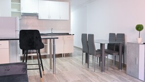 Una cocina moderna con armarios blancos, una silla negra y una mesa de comedor con cuatro sillas.
