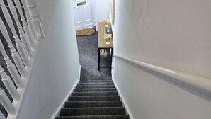 Un escalier recouvert de moquette, avec des murs blancs et une table en bois au sommet.