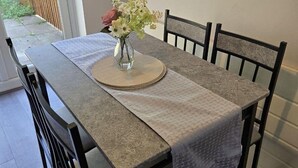 Une table à manger avec un set de table, un vase de fleurs et des chaises.