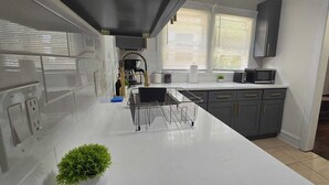 A modern kitchen with grey cabinets, a white countertop, and a microwave. - 2024 Remodeled 2bedroom in West CLE (Cleveland)