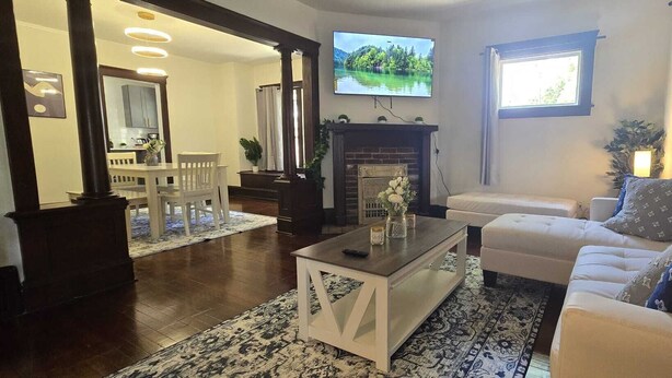 A living room with a fireplace, a TV, a sofa, and a dining area with a table and chairs. - 2024 Remodeled 2bedroom in West CLE (Cleveland)