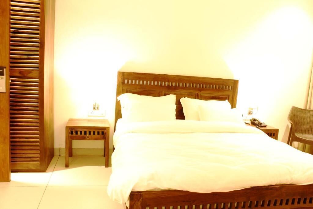 A neatly made bed with white linens, a wooden headboard, and two bedside tables with lamps.