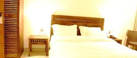 A neatly made bed with white linens, a wooden headboard, and two bedside tables with lamps.