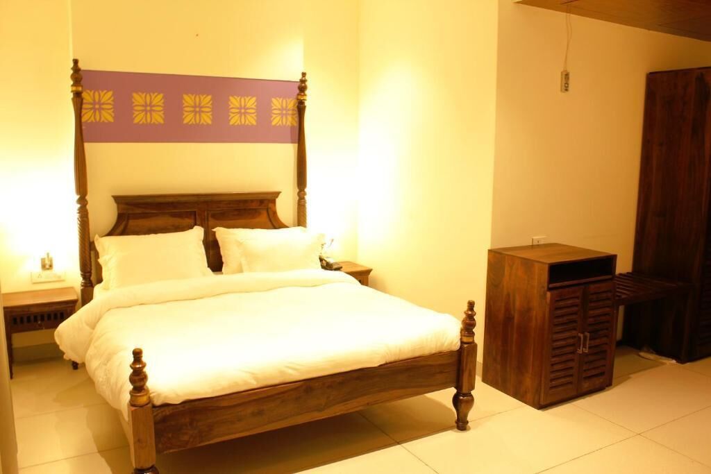 Un dormitorio con una cama de madera, una mesita de noche, un aparador y un panel decorativo púrpura sobre la cama.