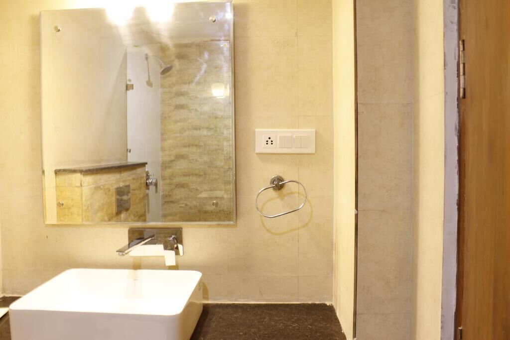 A bathroom with a white sink, a mirror, and a towel ring on the wall.