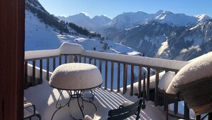 A balcony with a snow-covered table and bench, overlooking a mountainous landscape. - Spacious apartment with beautiful views near slopes (Villard-Reculas)
