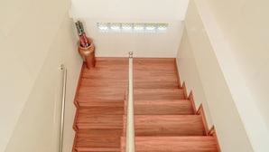 A staircase with a wooden finish and a handrail, leading to a room with a sign reading "ashanti Guest House". - Ashanti Guest House Ubud (Ubud)