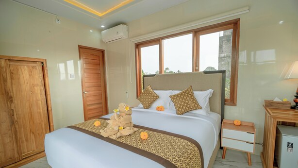 A hotel room with a large bed, wooden wardrobe, bedside table, and a window with a view. - Ashanti Guest House Ubud (Ubud)