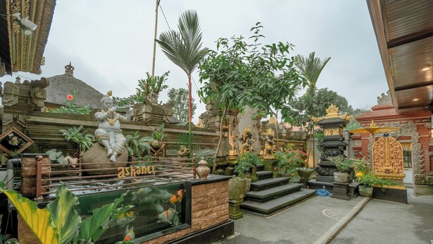 A temple courtyard with statues, a koi pond, and traditional architecture. - Ashanti Guest House Ubud (Ubud)