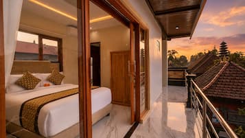 Habitación de hotel con cama, baño y balcón con vistas a edificios tradicionales.