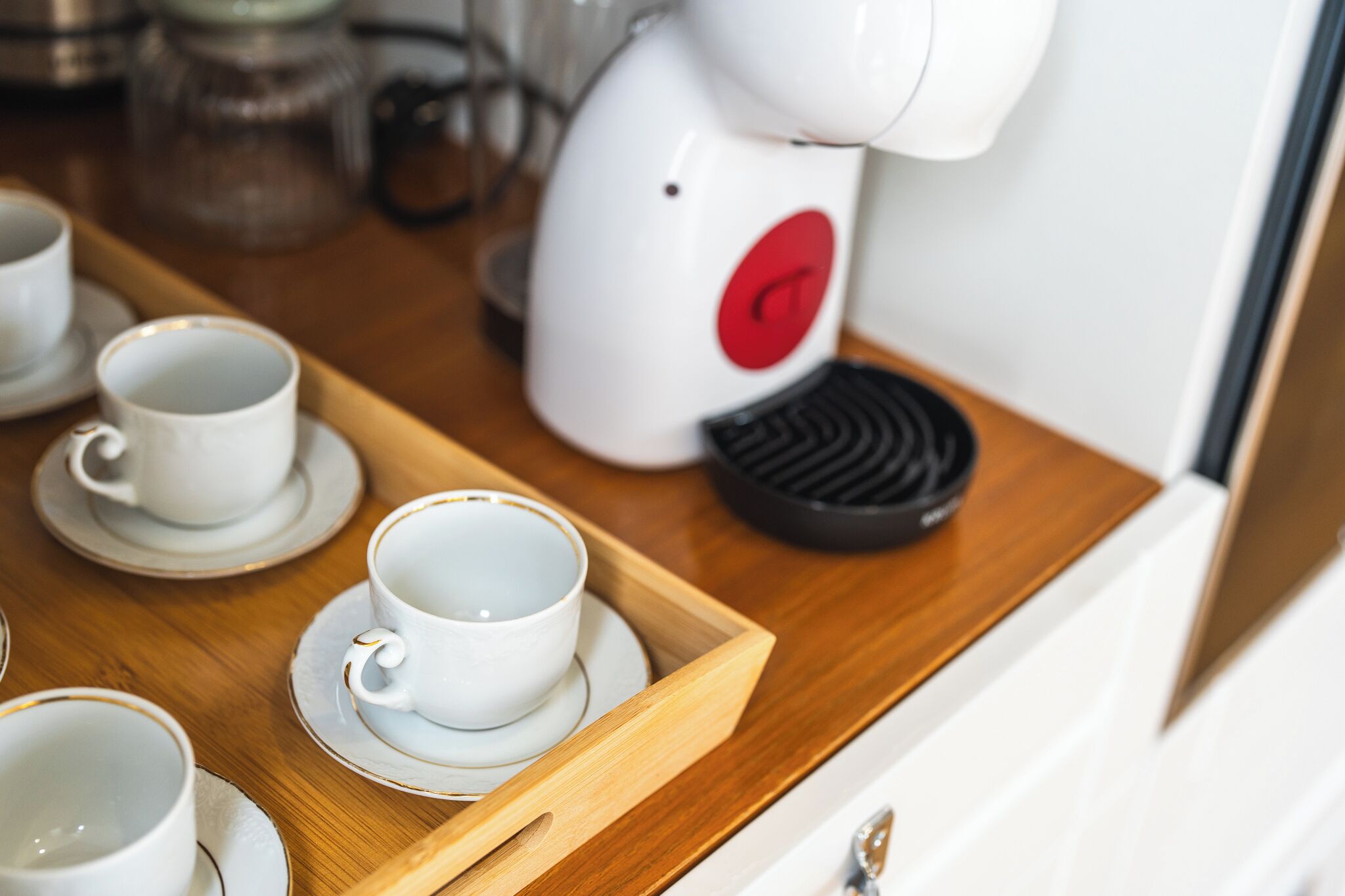 A coffee machine on a wooden tray with white cups and saucers.