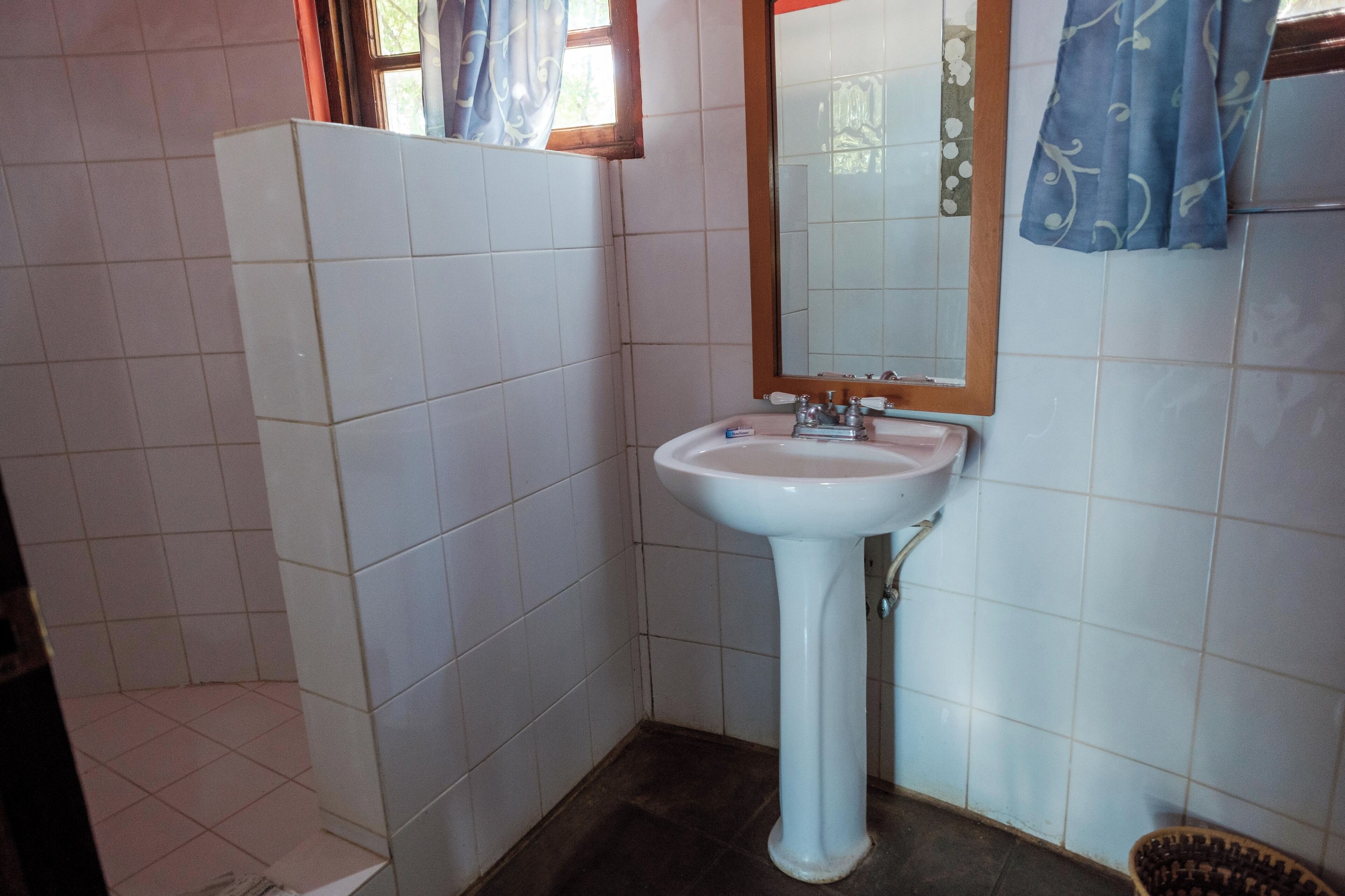 A bathroom with a white sink, a mirror, and tiled walls.