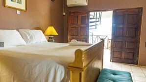 Una cama bien hecha con sábanas blancas, una lámpara de noche y un cabecero de madera.