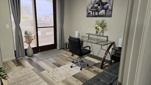 A modern office space with a glass desk, black office chair, and a piano painting on the wall. - Stylish & Prestigious! 2 Bed/2 Bath-On The Avenue (Fountain Hills)