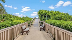 A pathway leading to a building with a wooden railing and benches on either side.