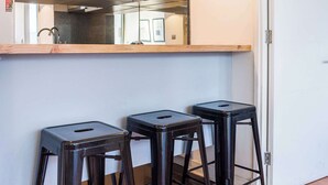 Une cuisine équipée d’un four à micro-ondes, d’un évier à deux bacs et de deux tabourets de bar.