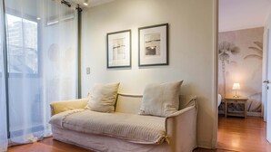 Une pièce avec un canapé, une lampe et deux tableaux encadrés accrochés au mur.