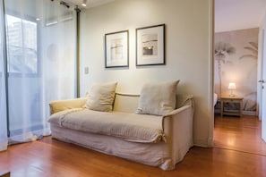 A room with a sofa, a lamp, and two framed pictures on the wall.