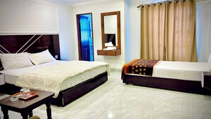 Habitación de hotel con dos camas, un escritorio, un espejo y una ventana con cortinas.