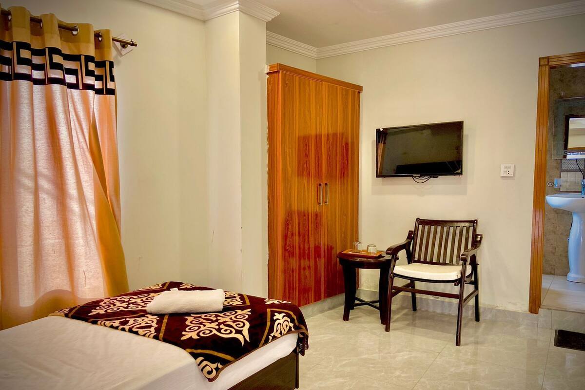 Une chambre d’hôtel avec un lit, une chaise, une télévision et une salle de bain.