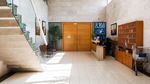 A spacious lobby with a staircase, a reception desk, and a large wooden door.