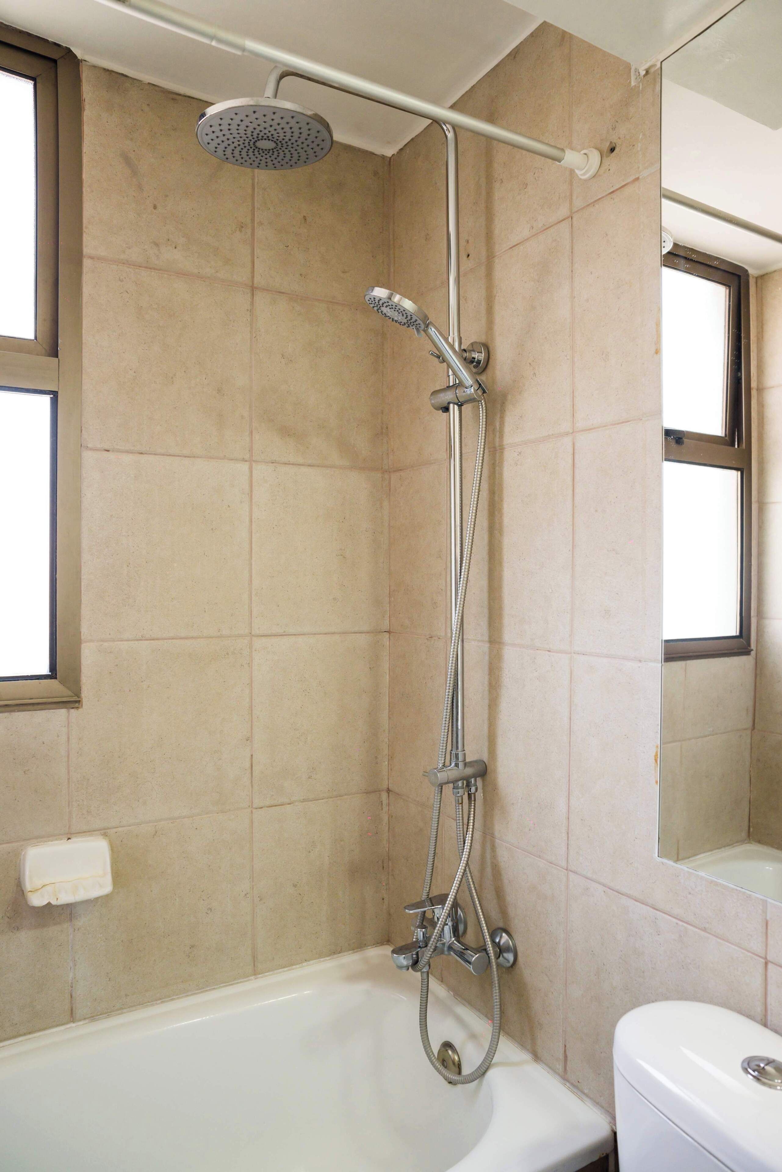A bathroom with a shower, toilet, and a window.