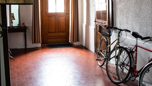 A hallway with a wooden door, a bicycle, and a lamp. - Large apartment with raised garden in the heart of Burgundy (Montcenis)