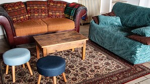 A living room with a sofa, ottoman, and coffee table. - Large apartment with raised garden in the heart of Burgundy (Montcenis)