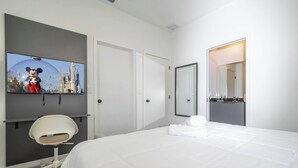 Une chambre d’hôtel avec un lit, un téléviseur diffusant un dessin animé, une chaise et une porte de salle de bain.