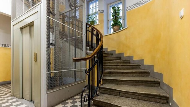 A staircase with a metal railing, a checkered floor, and a yellow wall.