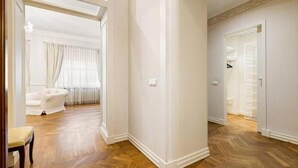 A spacious room with wooden flooring, a white wall, and a door leading to another room.