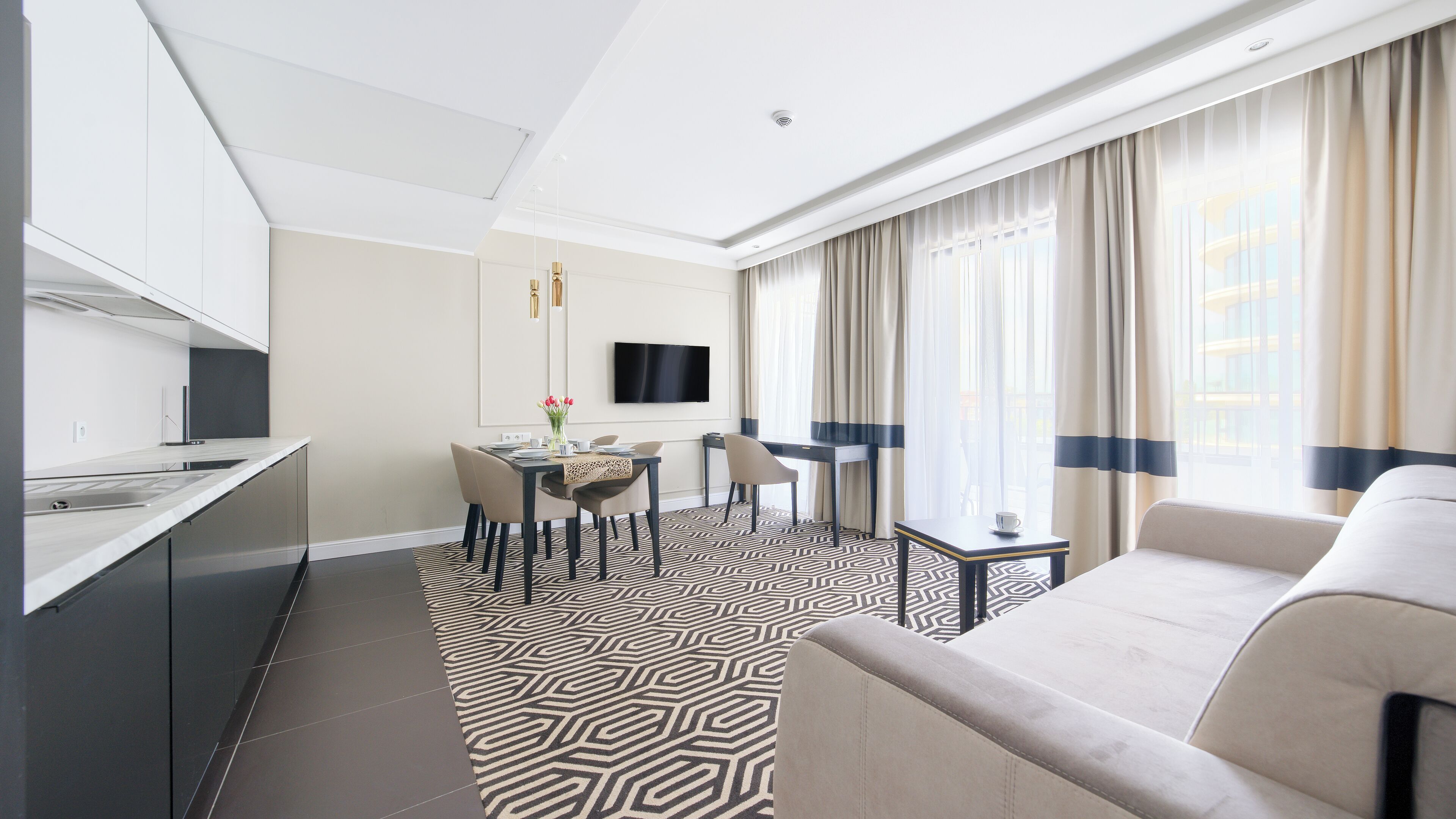 Ein modernes Hotelzimmer mit Küche, Essbereich und Wohnbereich.
