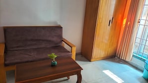 Una sala de estar con un sofá, una mesa de centro de madera y una planta en maceta.