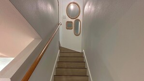 A wooden staircase with a handrail, white walls, and a small mirror on the wall. - 2 bedroom 1.5 bath townhome 1150 sqft (Rockport)