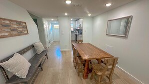 A dining area with a wooden table and benches, a bench with a cushion, a framed fish artwork on the wall, and a mirror. - 2 bedroom 1.5 bath townhome 1150 sqft (Rockport)