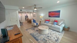 A modern living room with a sofa, coffee table, and a dining area with chairs and a table. - 2 bedroom 1.5 bath townhome 1150 sqft (Rockport)