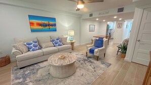 A living room with a sofa, armchair, coffee table, and artwork on the wall. - 🌊 Welcome to Little Bay Landing in Rockport, Texas! 🌊 (Rockport)