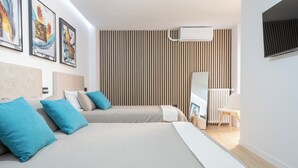 A modern hotel room with two beds, a TV, a radiator, and a wooden slat wall.