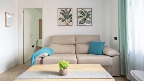 A living room with a beige sofa, a coffee table, and two framed botanical prints on the wall.