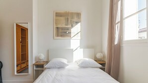 Un dormitorio con una cama, dos mesitas de noche, un espejo y una ventana.