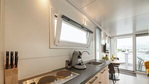 Una cocina moderna con estufa integrada, cafetera y ventana con persianas.