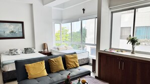 A modern hotel room with a bed, sofa, and a view of the city.